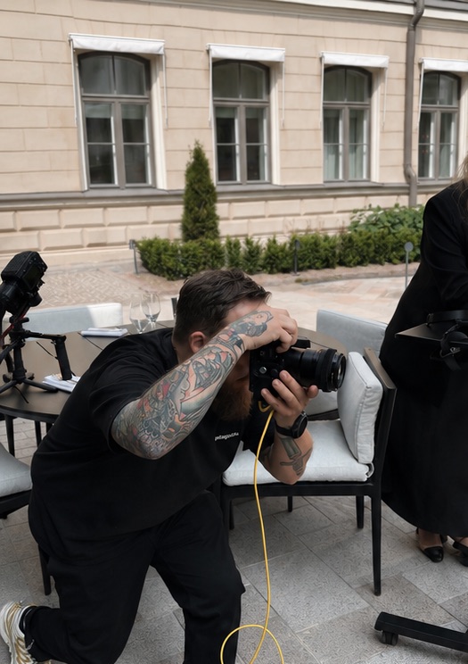 A photographer at work over a courtyard table set-up on a campaign shoot.