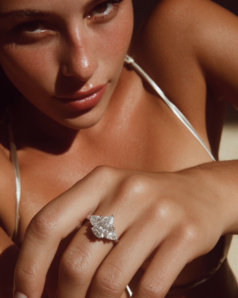 An ad visual: a diamond ring in hard sunlight, worn at the beach
