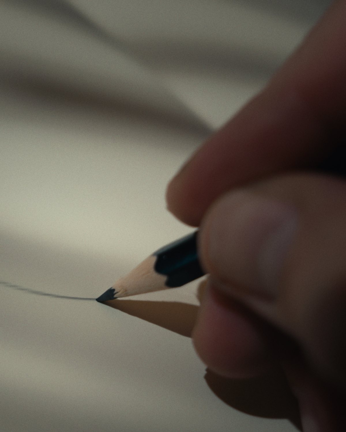A pencil drawing the first curve of a ring design on paper