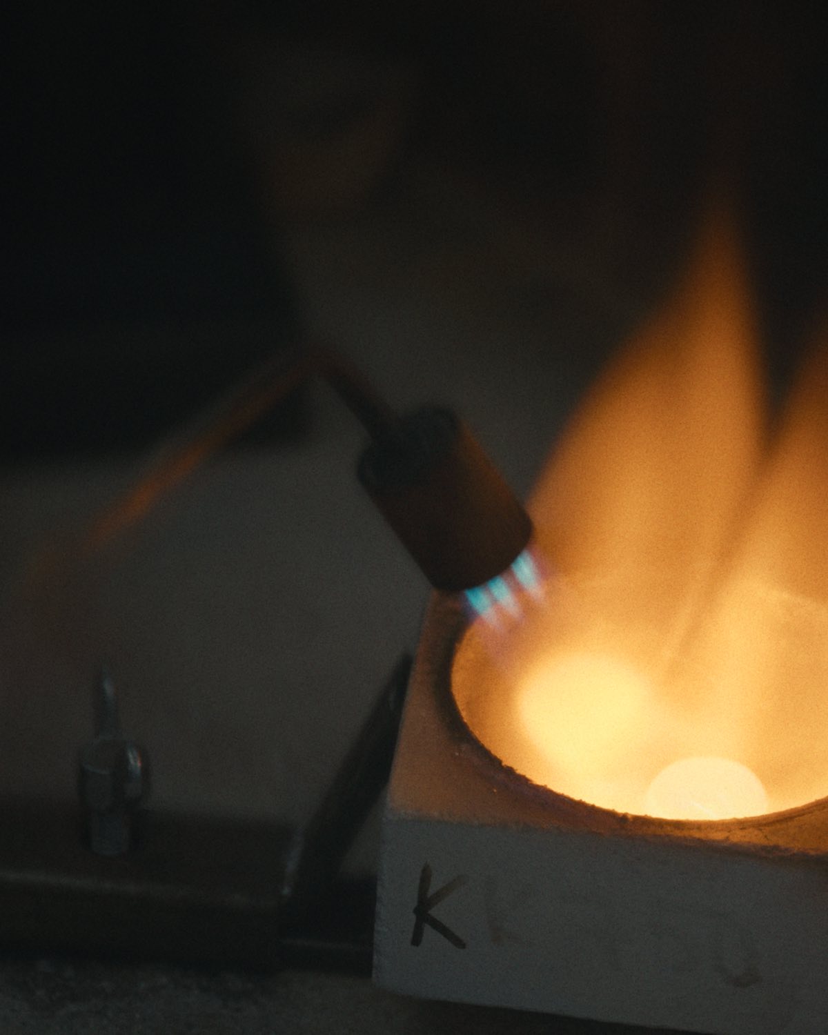A torch flame over a crucible on the goldsmith's bench