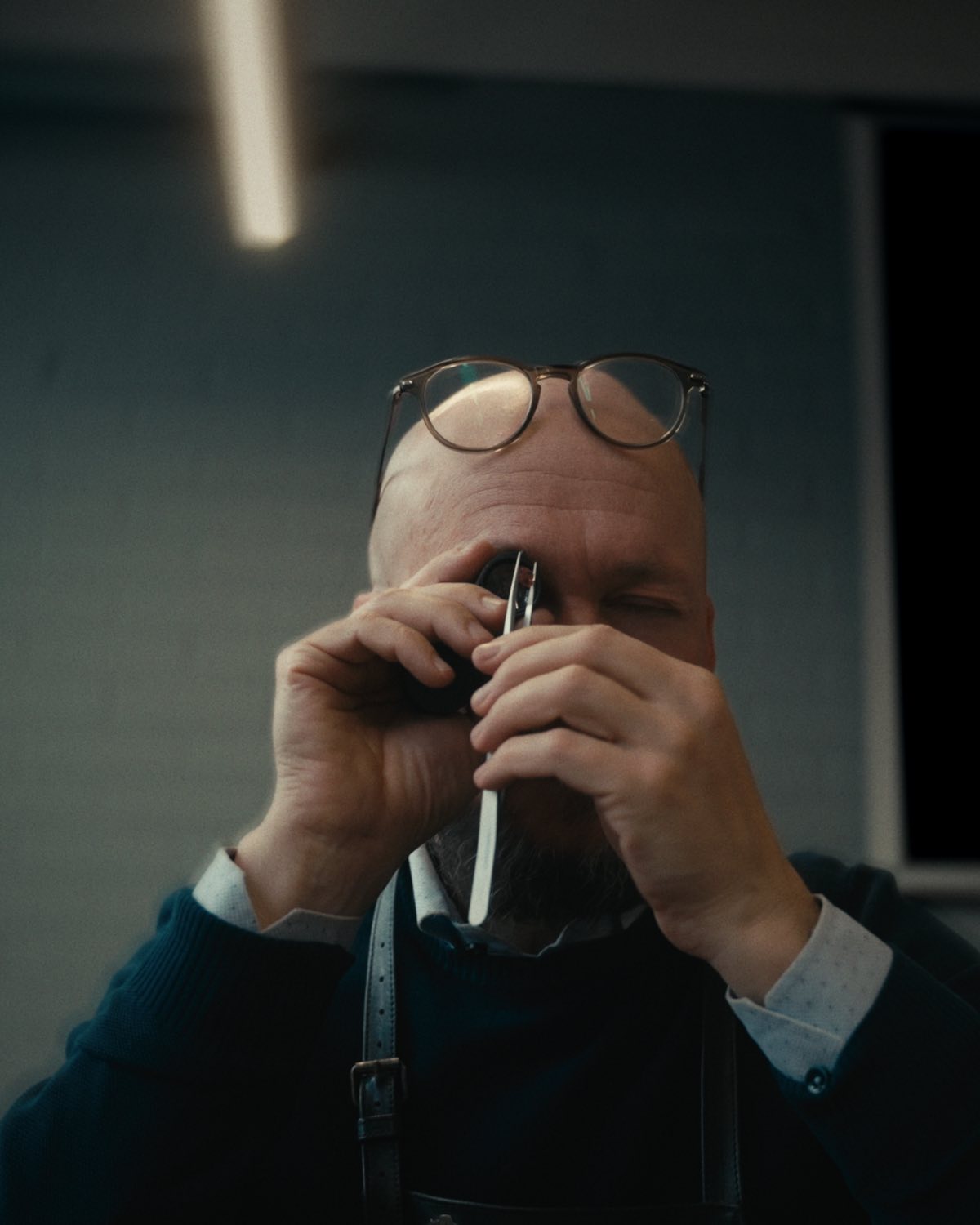 The goldsmith raising a stone in tweezers to his eye