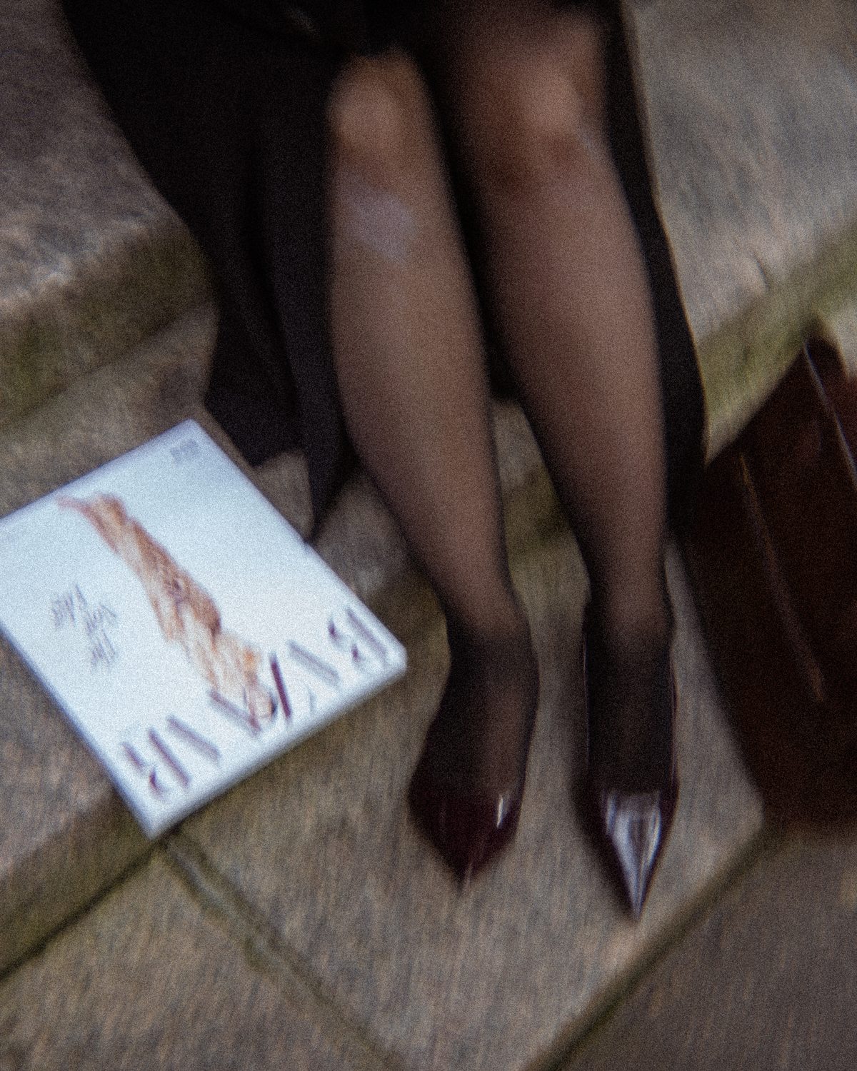 An overhead frame of heels on stone steps beside a magazine and a bag