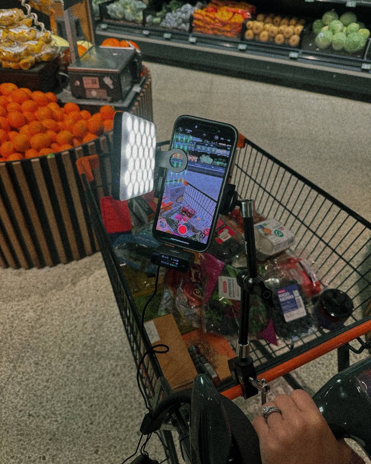 A phone rigged to a shopping trolley with an LED panel, recording the aisle