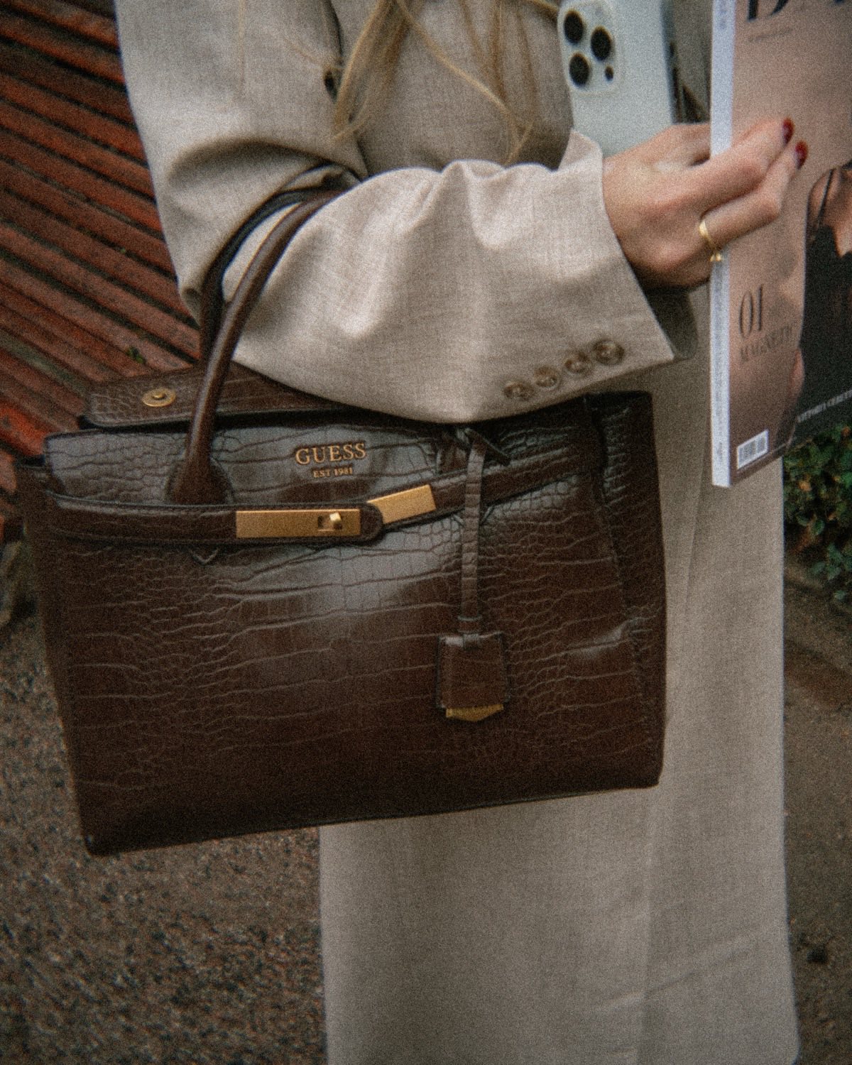 A croc-leather handbag and a fashion magazine in hand, from a campaign shoot